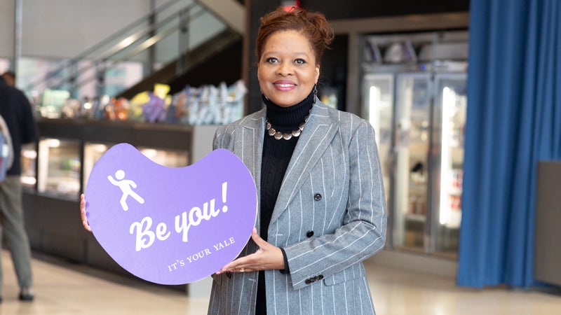Image of a woman holding a sign that says "Be You"