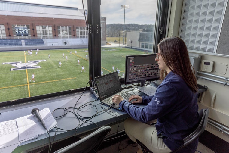 Mary Boudreau cues the team’s practice playlist over the stadium’s sound system