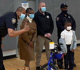 Members of the YPD and YAAA present a new bike to young student at East Rock Community Magnet School in New Haven