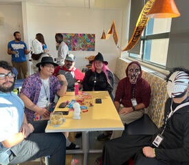 IT staff dressed up for a Halloween party, sitting around a table.