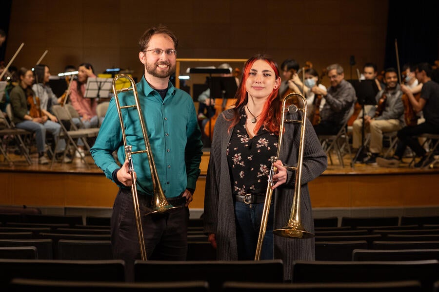 Anjelica Martin and Matthew Kluko standing in front of the Yale Medical Symphony Orchestra.