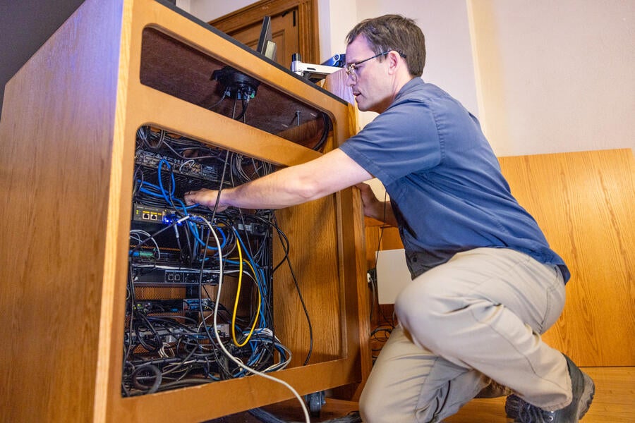 Person fixing technology underneath a classroom podium.
