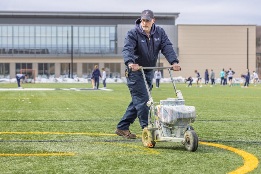 Facilities worker painting the lacrosse turf before a game