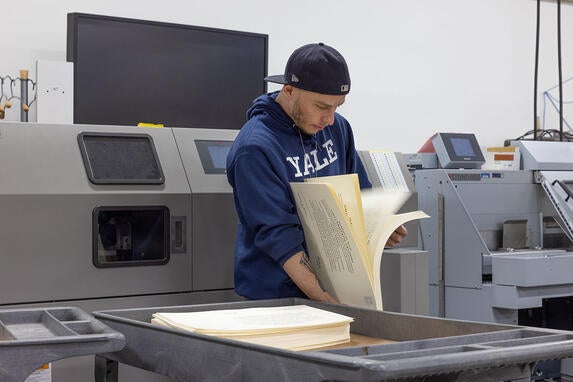 image of Alex Nestir of YPPS spot-checking Yale College diplomas for accuracy before they are trimmed to size.