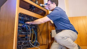 Person fixing technology underneath a classroom podium.