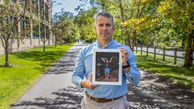 Michael van Emmenes holds a photo of his finish at the Ironman Lake Placid