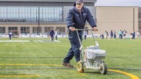 Facilities worker painting the lacrosse turf before a game