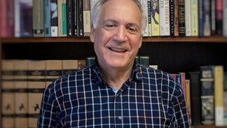Image of Roger Cohn in front of inside in front of books.